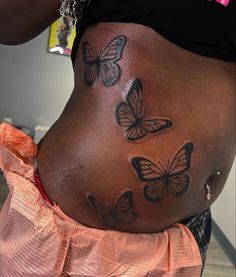 a pregnant woman with butterfly tattoos on her stomach and belly is seen from the back