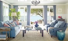 a living room with blue couches and curtains on the window sill in front of two windows