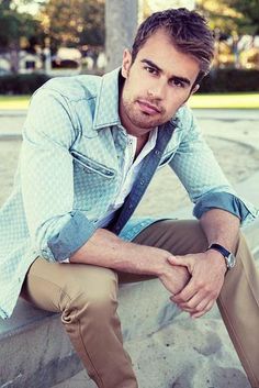 a man sitting on the ground with his arms crossed and wearing a shirt and tie