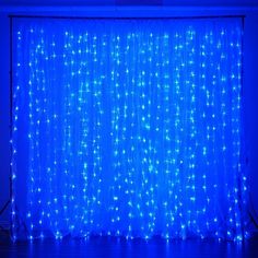 a blue curtain with white dots on it in front of a black wall and floor