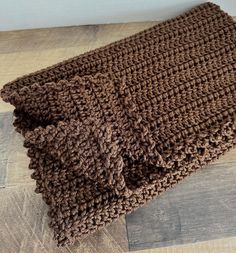 a brown knitted blanket sitting on top of a wooden floor