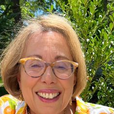 an older woman wearing glasses smiling for the camera