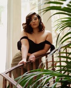 a woman in black top leaning on railing next to plants