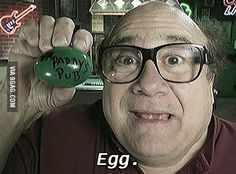 an old man with glasses holding up a green egg