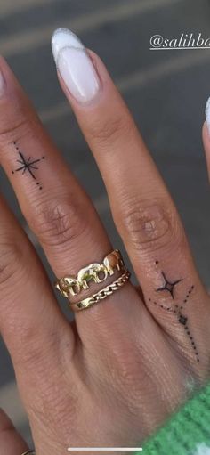 a woman's hand with tattoos on it and a cross tattoo on the middle finger