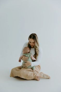 a woman sitting on the floor holding a baby