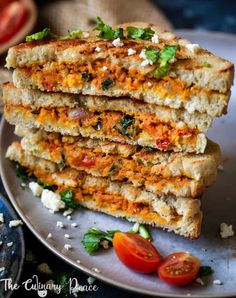 a stack of grilled cheese sandwiches on a plate with tomatoes and parmesan