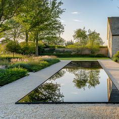 a large pool surrounded by gravel and trees in front of a house with a stone patio