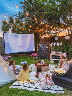 people sitting on the grass watching movies in their backyard