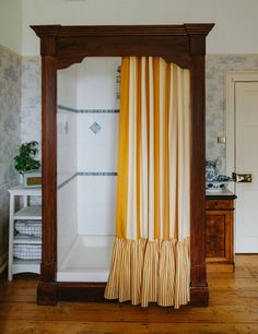 a bathroom with a shower, toilet and sink in the corner next to a wooden floor