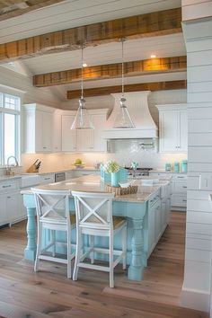 a kitchen with white cabinets and blue island