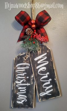 two christmas tags hanging on the wall with holly and pineconis attached to them