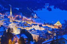 the city is lit up at night in the snow