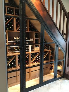 a room filled with lots of bottles of wine on shelves next to a stair case