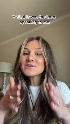 a woman with long hair standing in front of a lamp and holding her hands up