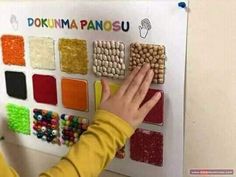 a young child is playing with some colorful beads on a wall mounted display in front of her