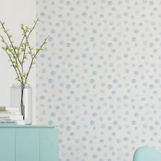 a vase filled with flowers sitting on top of a blue dresser next to a wall