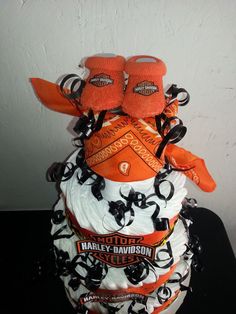 an orange and white diaper cake with baby booties on it's top