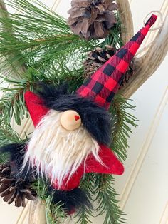 a christmas wreath with a red and black gnome ornament hanging from it's side