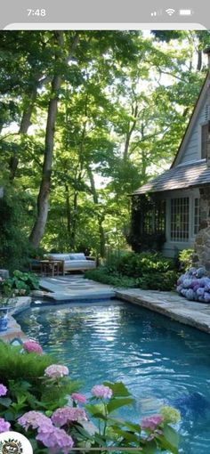 an outdoor swimming pool surrounded by trees and flowers in front of a house with stone steps leading up to it