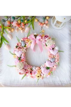 a wreath with pink flowers and greenery on a white furnishing area next to other decorations