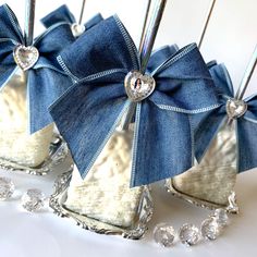 three blue bows are on top of silver square holders with crystal beaded balls around them