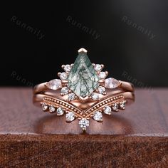 a close up view of a green and white diamond ring on top of a wooden surface