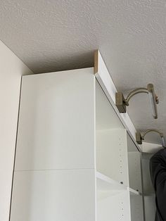 a person is standing in front of a white cabinet with shelves and hooks on it