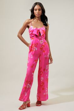 Add the sweetest pop of pink to your wardrobe in the Cherry Blossom Raleigh Jumpsuit. Sleek satin covered in pink tonal sakura blossoms decorate a straight leg jumpsuit. It features a bow tie detail at the chest that sits atop a little cut out. - Lined- Cut out- Pockets- Zipper- Color: Pink Red MultiSize + Fit - Model is 5'10" and wearing size XS- Measurements taken from size S - Waist: 14 1/2"- Inseam: 30 3/4" Fabric Self: 100% Polyester, Lining: 97% Polyester, 3% Spandex Style Number STP7360P Chic Spring Satin Jumpsuits And Rompers, Spring Floral Print Overall Jumpsuits, Spring Floral Print Overall Jumpsuits And Rompers, Chic Floral Print Jumpsuits And Rompers For Spring, Feminine Sleeveless Jumpsuits For Spring, Spring Party Satin Jumpsuits And Rompers, Feminine Sleeveless Jumpsuits And Rompers For Spring, Satin Jumpsuits And Rompers For Spring Party, Elegant Floral Jumpsuits And Rompers For Spring