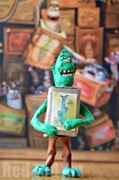 a green toy holding a box with an image of a monster on it's face