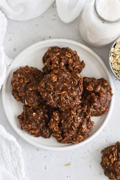 chocolate oatmeal cookies on a white plate next to a glass of milk