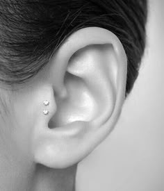 a woman's ear is shown with two small diamond studs on the side