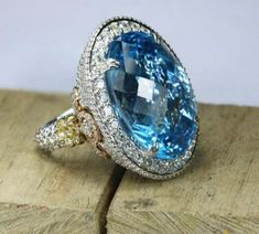 a blue and white ring sitting on top of a piece of wood with diamonds around it