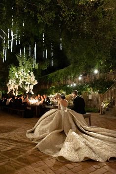 a bride and groom sitting at a table in the middle of an outdoor dining area