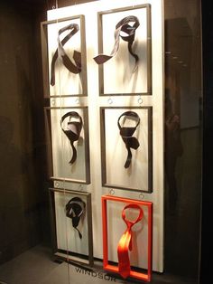 a display case with various pieces of art hanging on it's sides and ties attached to the wall