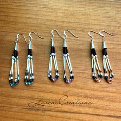 four pairs of beaded earrings sitting on top of a wooden table