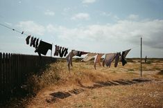 clothes hanging out to dry on a line in an open field with dirt and grass