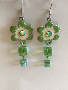 These earrings are made with green Swarovski Crystals cubes and silver colored earring hooks. The flower are enameled with green and white enamel. If you have any questions or concerns feel free to contact owner and designer at hannahsjeweltique@gmail.com Green Flower Earrings, Envelope Necklace, Pineapple Bracelet, Swarovski Crystal Drop Earrings, Cameo Bracelet, Sunflower Earrings, Silver Earrings Handmade, Costume Jewelry Earrings, Crystal Dangle Earrings