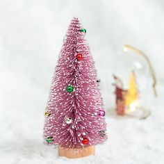 a small pink christmas tree sitting in the snow