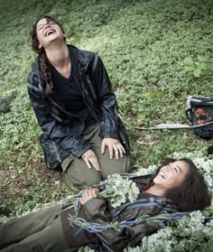 two people laying on the ground with flowers in their hands