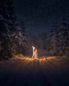 a man and woman standing in the snow at night