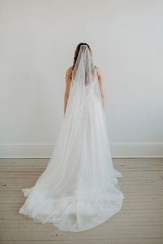 a woman in a wedding dress with a veil on her head looking down at the floor