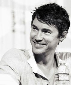 a black and white photo of a smiling man with a bottle of water in his hand