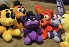 several stuffed animals are lined up on the couch with their faces painted like cartoon characters