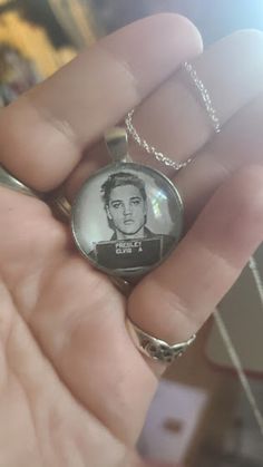 a person holding a necklace with a photo on it in their hand and wearing a chain