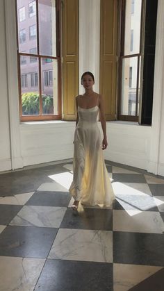 a woman in a white dress standing on a checkered floor