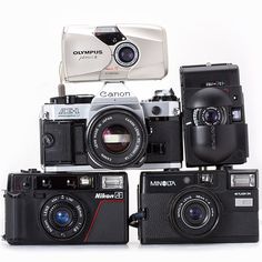 several different cameras sitting next to each other on a white surface with the same camera attached