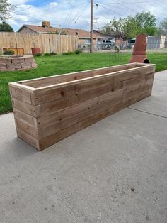 a wooden planter box sitting on top of a cement floor next to a yard