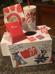 an open box with some food inside of it on a counter next to a cup