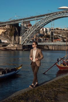 a man standing on the side of a river next to a bridge and boats in the water